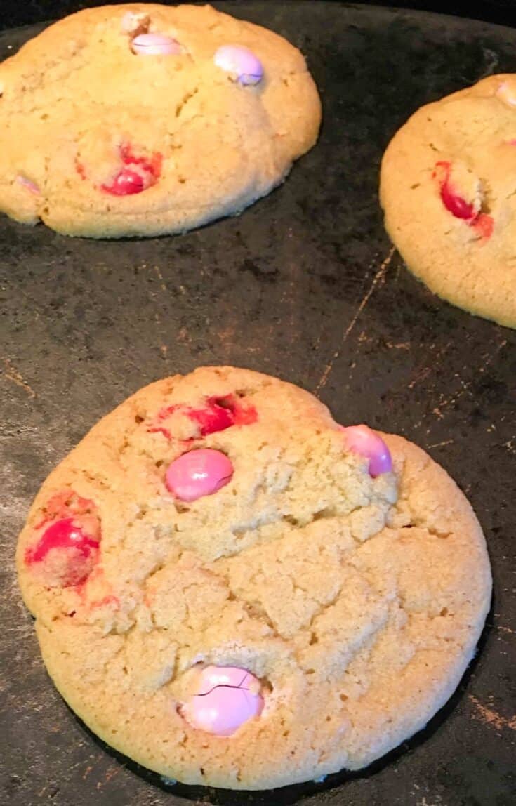 Pink and red M&M cookies on a cookie sheet