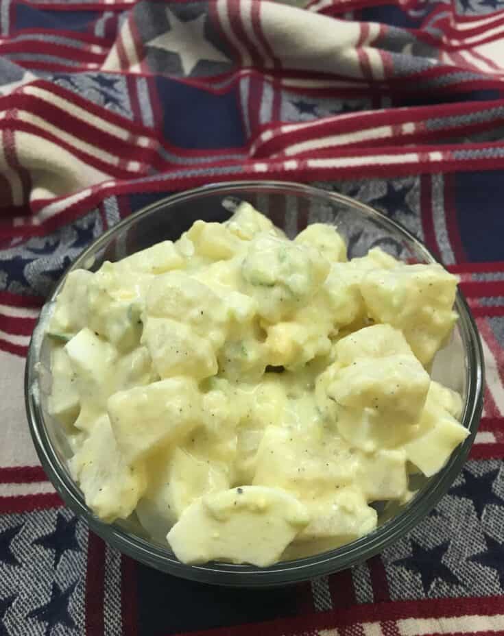 Potato salad with eggs in a glass bowl on a towel