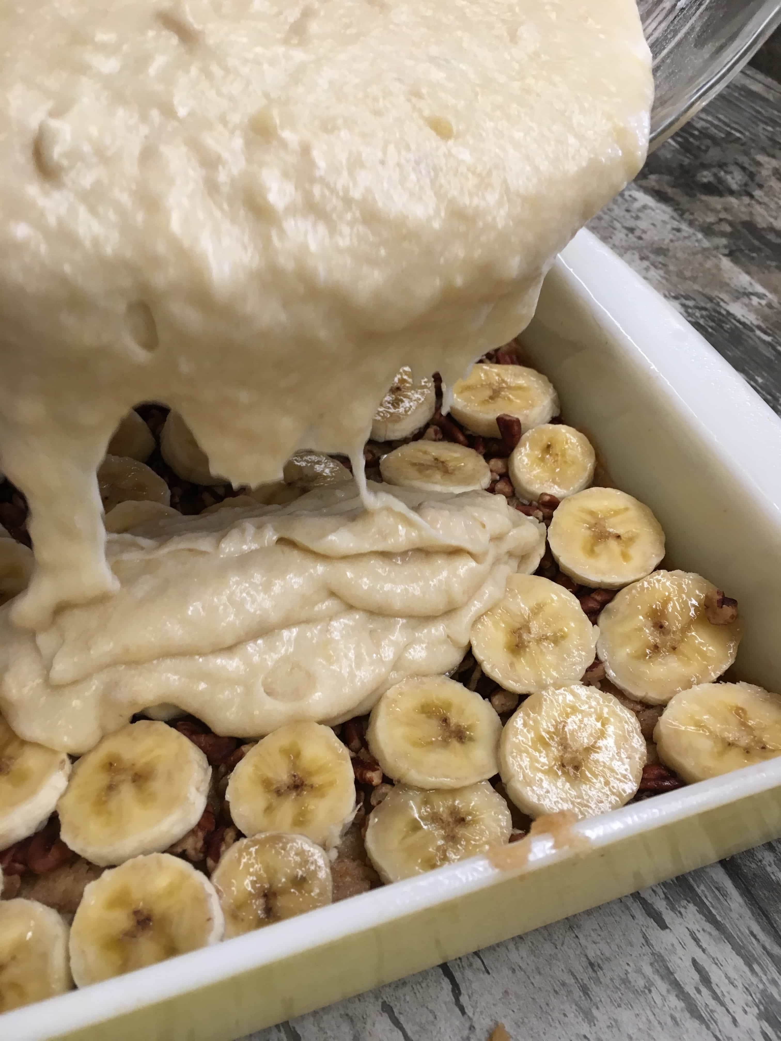 A casserole dish containing bananas and cake mix.