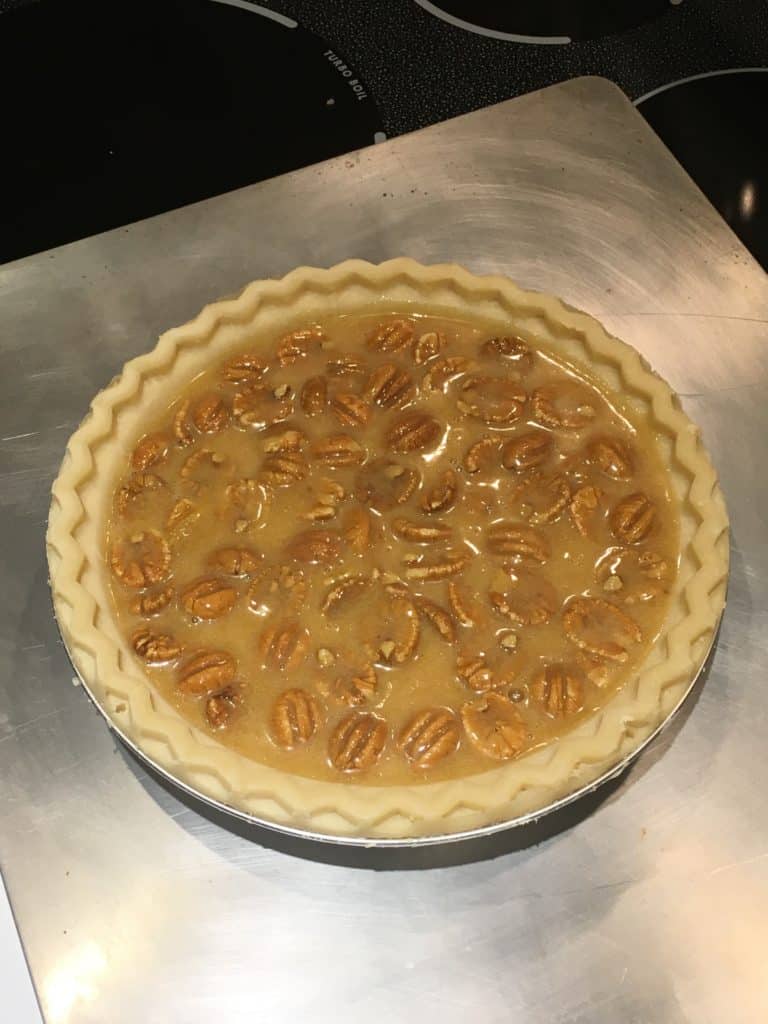 Uncooked pecan pie sitting on a cookie sheet.