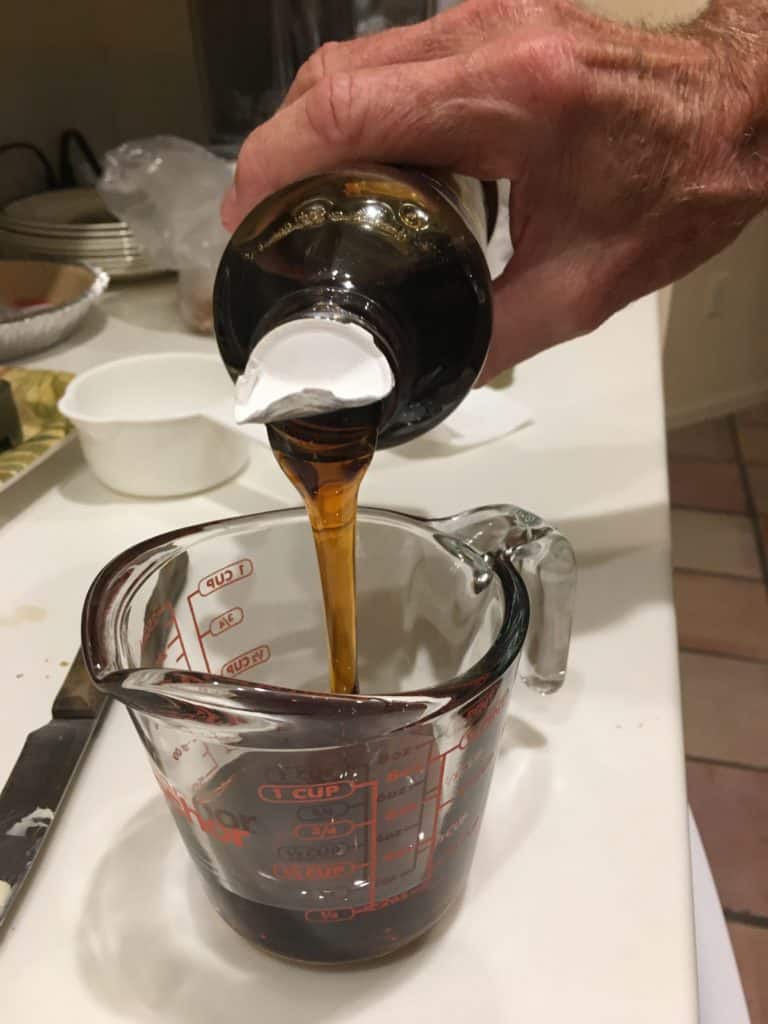 Pouring corn syrup into a glass measuring cup for pecan pie