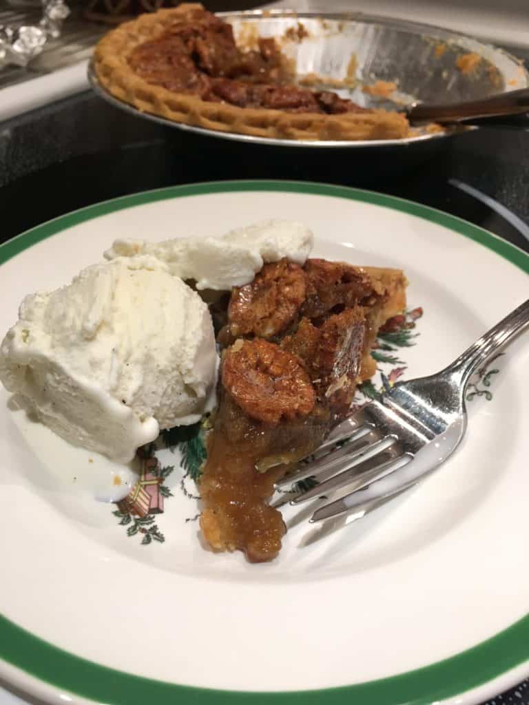 Pecan pie on a plate with ice cream and a fork