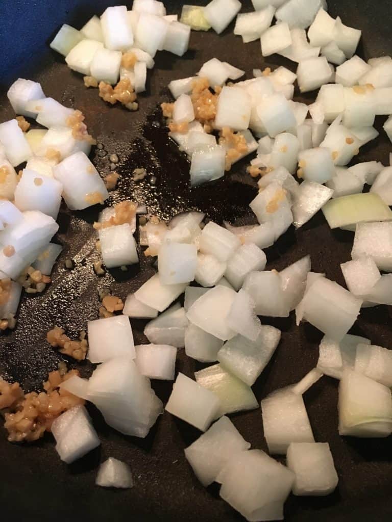 Diced onions and minced garlic in a skillet for easy hamburger soup. 