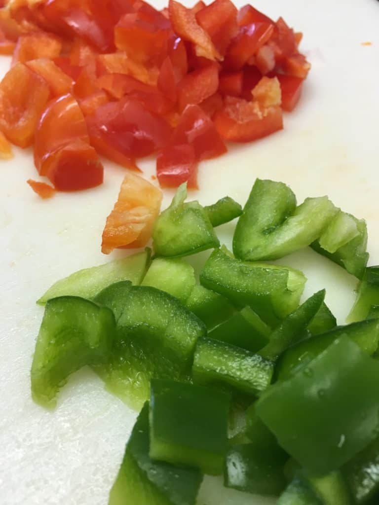 Red and green peppers cut up on a cutting board for hamburger soup