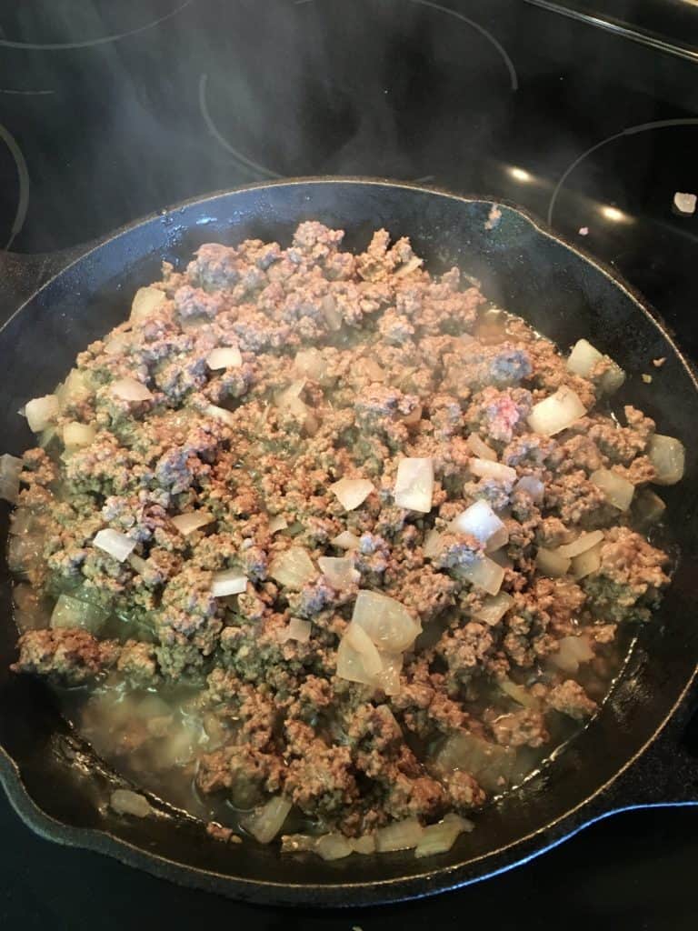 Ground beef, onions, and garlic cooking in a skillet for hamburger vegetable soup.