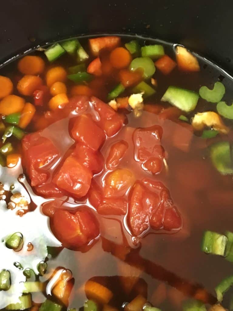 Tomatoes and vegetables in a pot for hamburger vegetable soup recipe. 