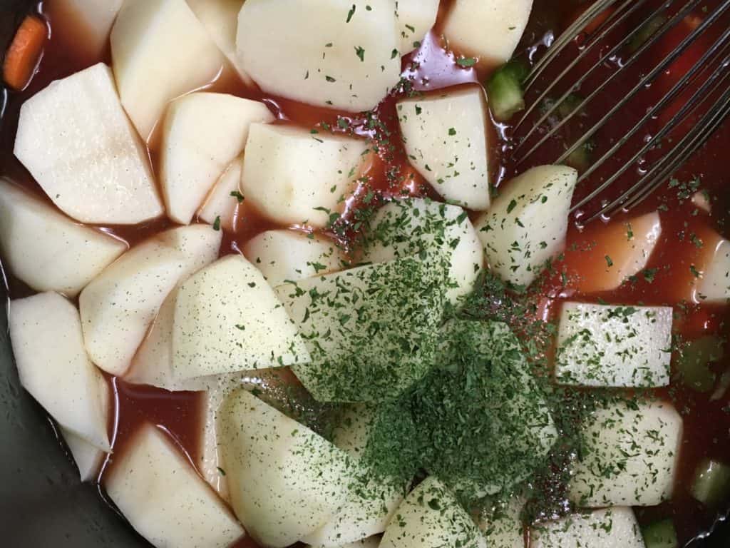 Diced potatoes in a saucepan with seasonings for hamburger and vegetable soup. 