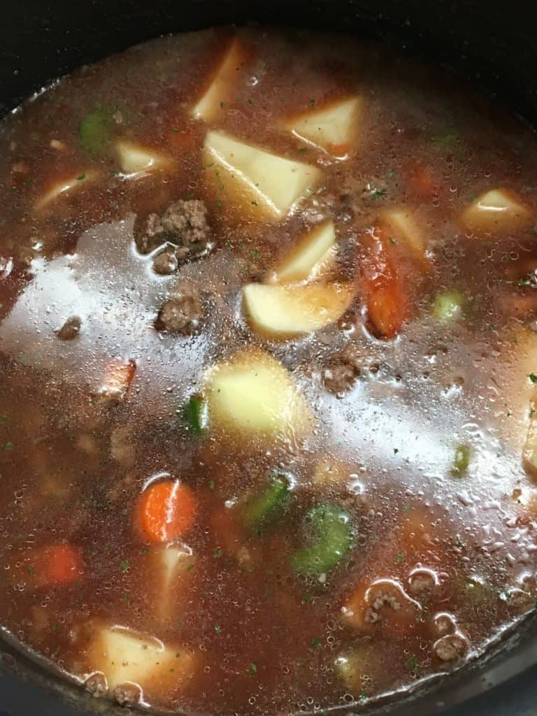 Beef soup recipe with vegetables and broth in a saucepan.