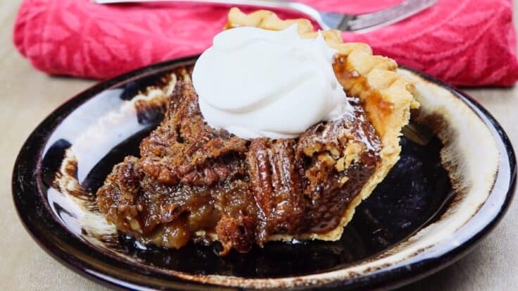 Pecan pie on a plate with a dollop of whipped cream