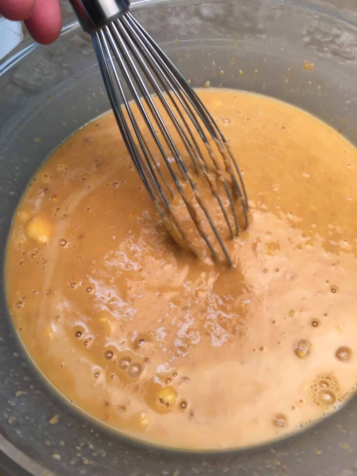 A whisk mixing the instant pudding in a glass bowl