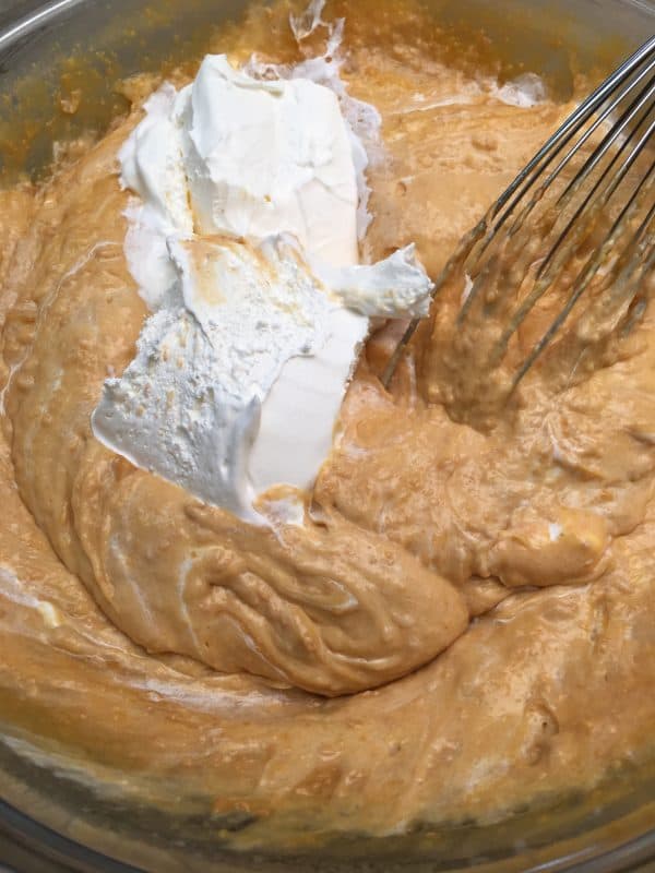 Instant pudding and whipped topping in a bowl with a whisk.