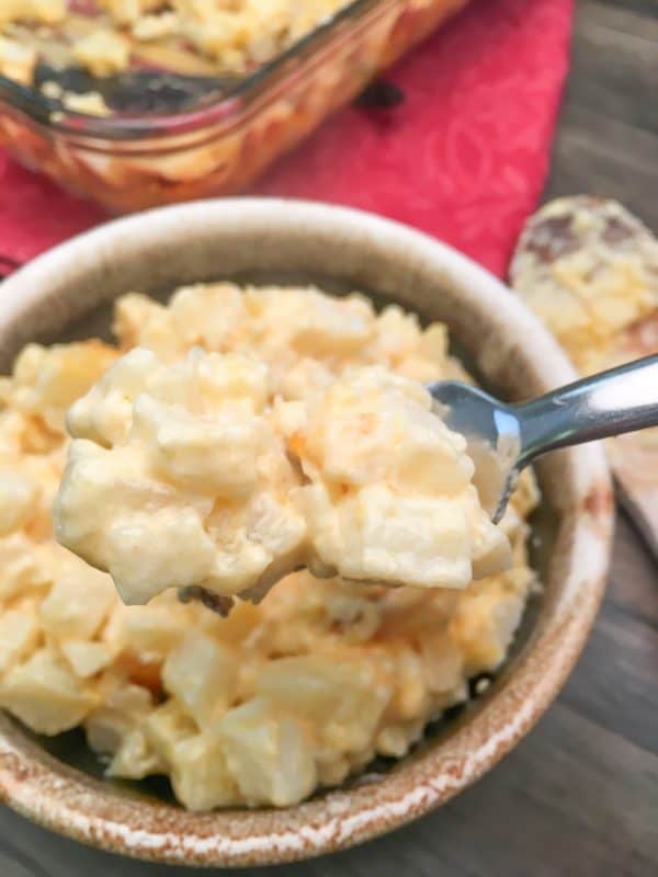 Easy cheesy potatoes on a fork next to a bowl.