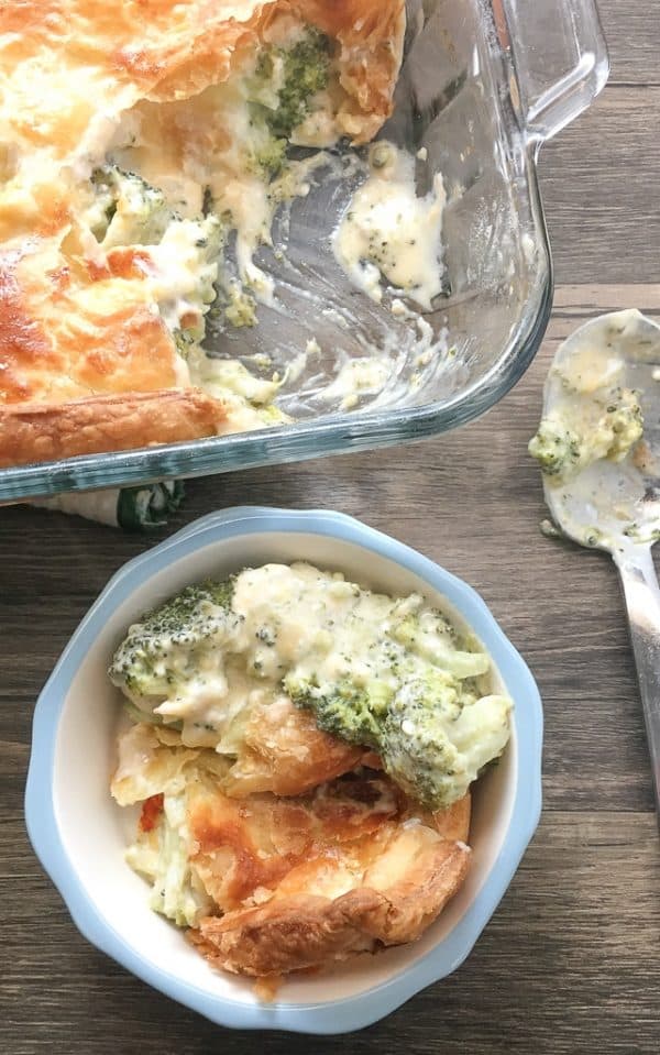 Broccoli cheese bake in a small bowl next to a casserole dish