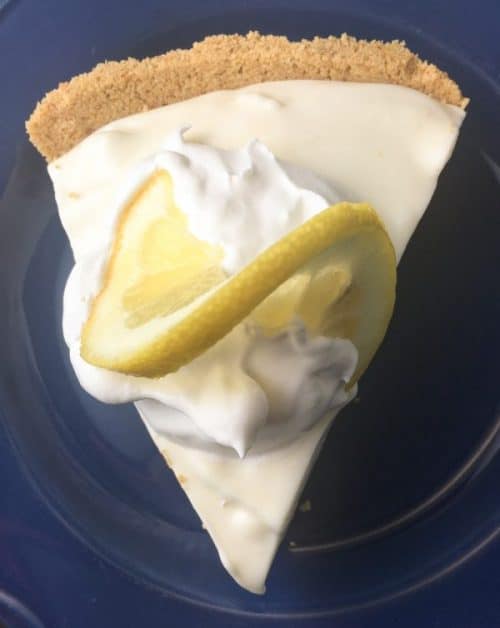 Lemon pie on a blue plate with a lemon on top.