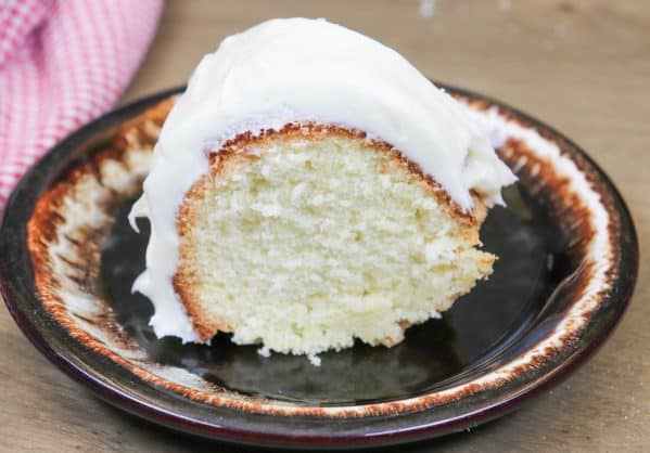 Picture of pound cake with cream cheese frosting on a plate. 