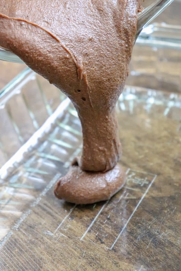 Picture of brownie batter being poured into a glass casserole dish.