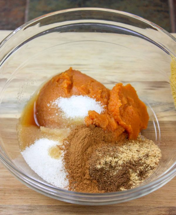 Picture of pumpkin, sugar, vanilla, and spices in a glass bowl.