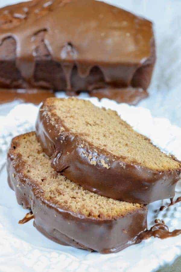 Picture of chocolate pound cake with frosting on a plate. 