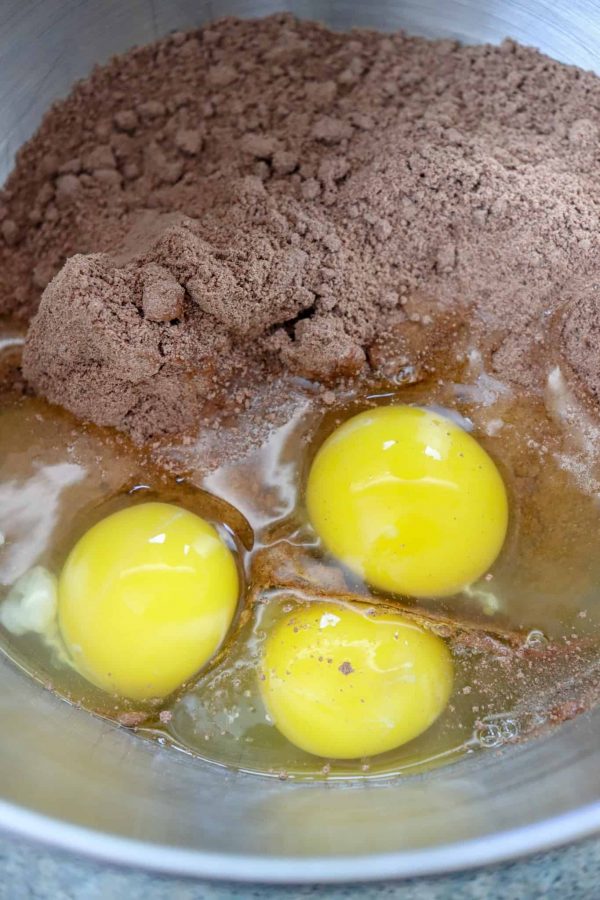 Picture of eggs and chocolate cake mix in a metal bowl.