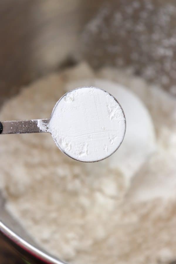 Picture of baking powder being poured into a bowl of flour. 