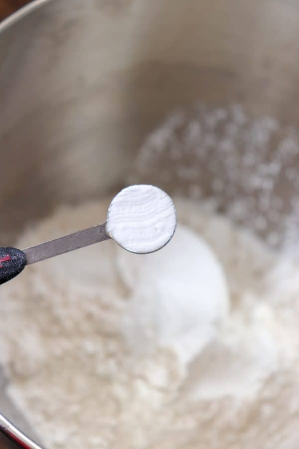 Picture of baking soda being poured into a bowl of flour. 