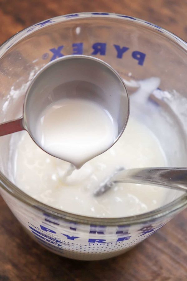 Picture of milk being poured into a mixing cup with powdered sugar.