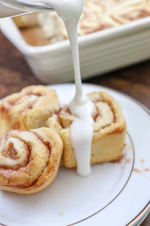 Picture of icing being poured over homemade cinnamon rolls.