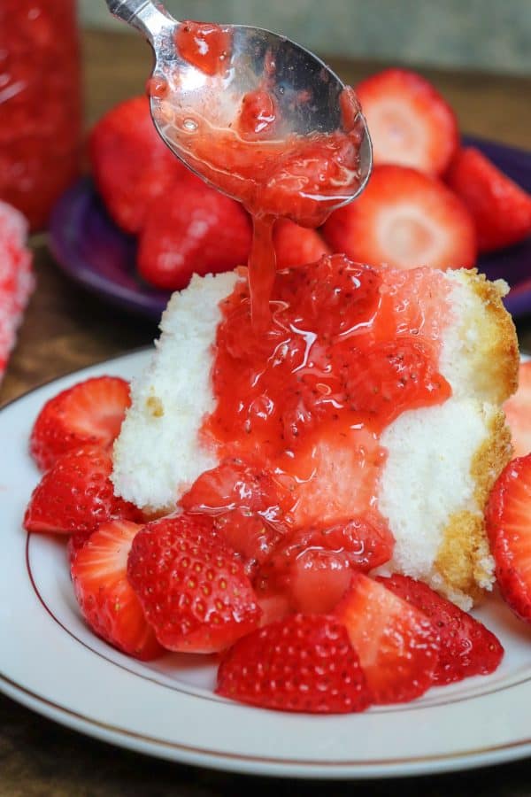 Picture of strawberries and strawberry syrup on top of angel food cake.