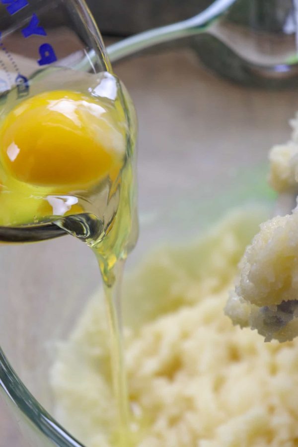 Picture of an egg being poured into a glass bowl. 