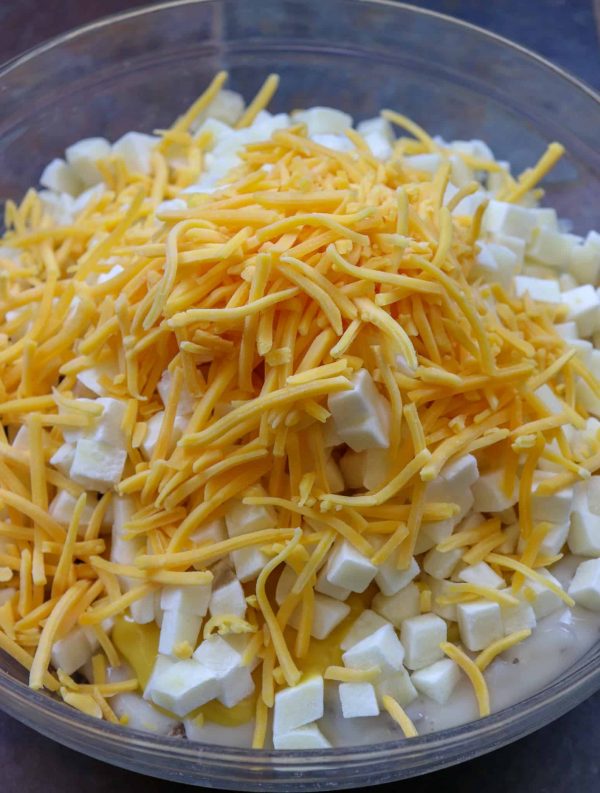 Picture of shredded cheddar cheese on top of a bowl of potatoes.