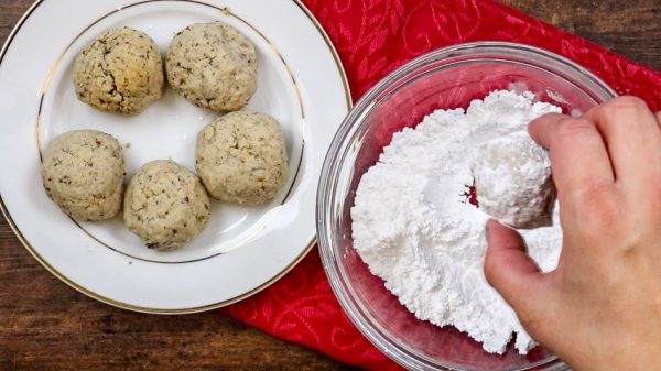 Picture of cookies being rolled in powdered sugar