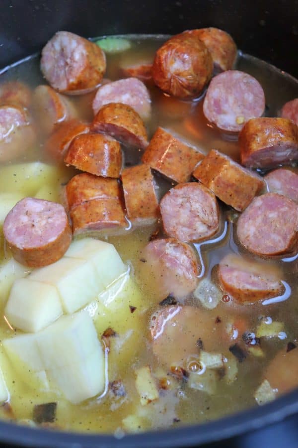 Picture of sausage, potatoes, and black eyed peas in a saucepan.