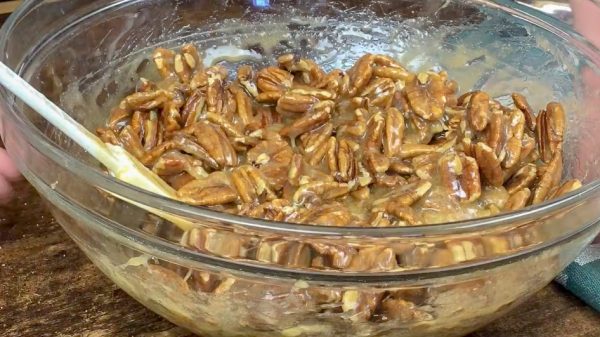 Picture of pecans with pecan pie ingredients in a bowl