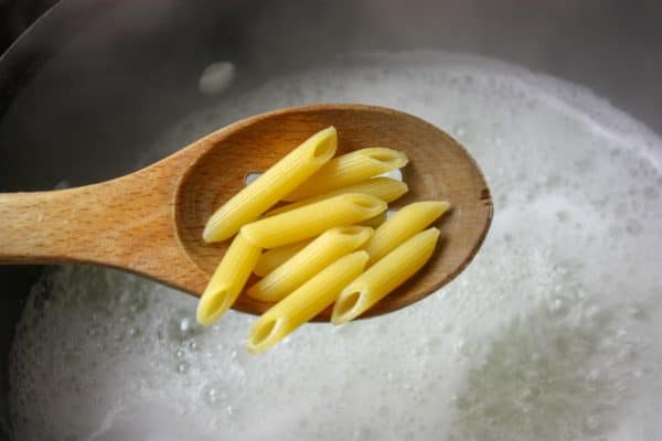 Picture of penne pasta on a wooden spoon.