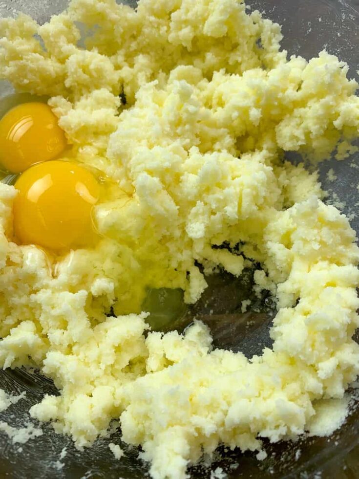 Sugar, butter, and eggs mixed together in a glass bowl