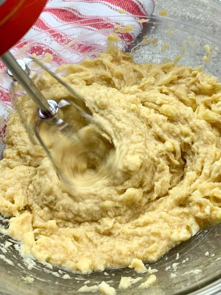 A hand mixer mixing the ingredients in a glass bowl for brookies