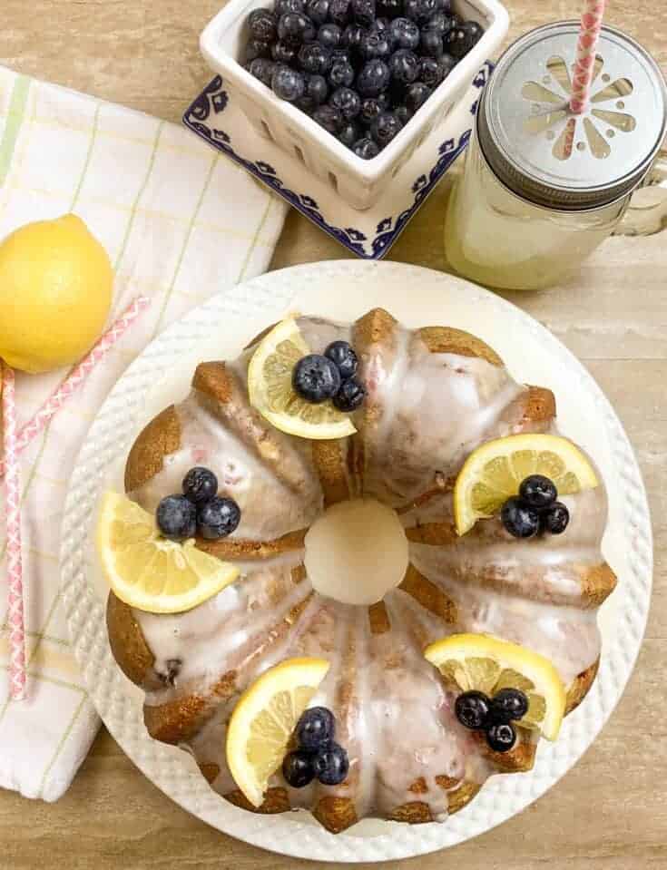 Lemon Blueberry Cake on a plate with blueberries and lemonade