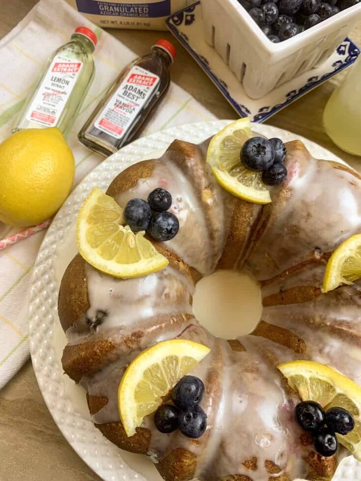 Lemon bundt cake on a plate with blueberries and vanilla and lemon extract