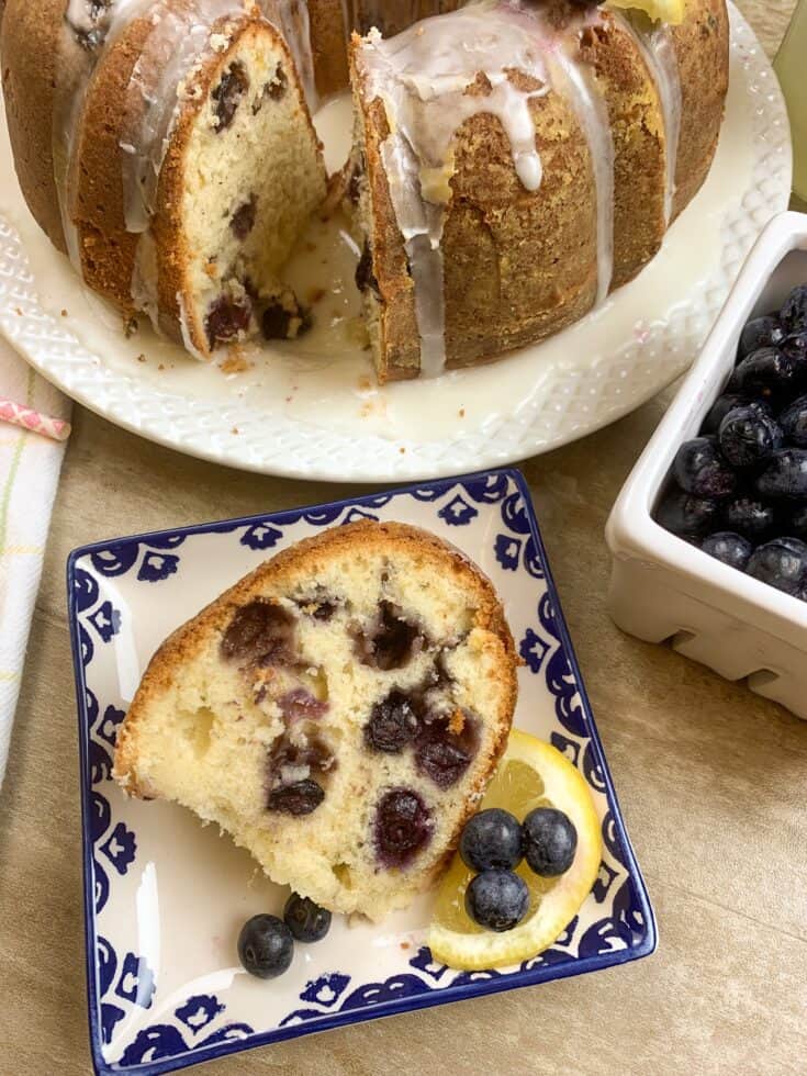 Lemon blueberry cake on a plate with lemons and blueberries