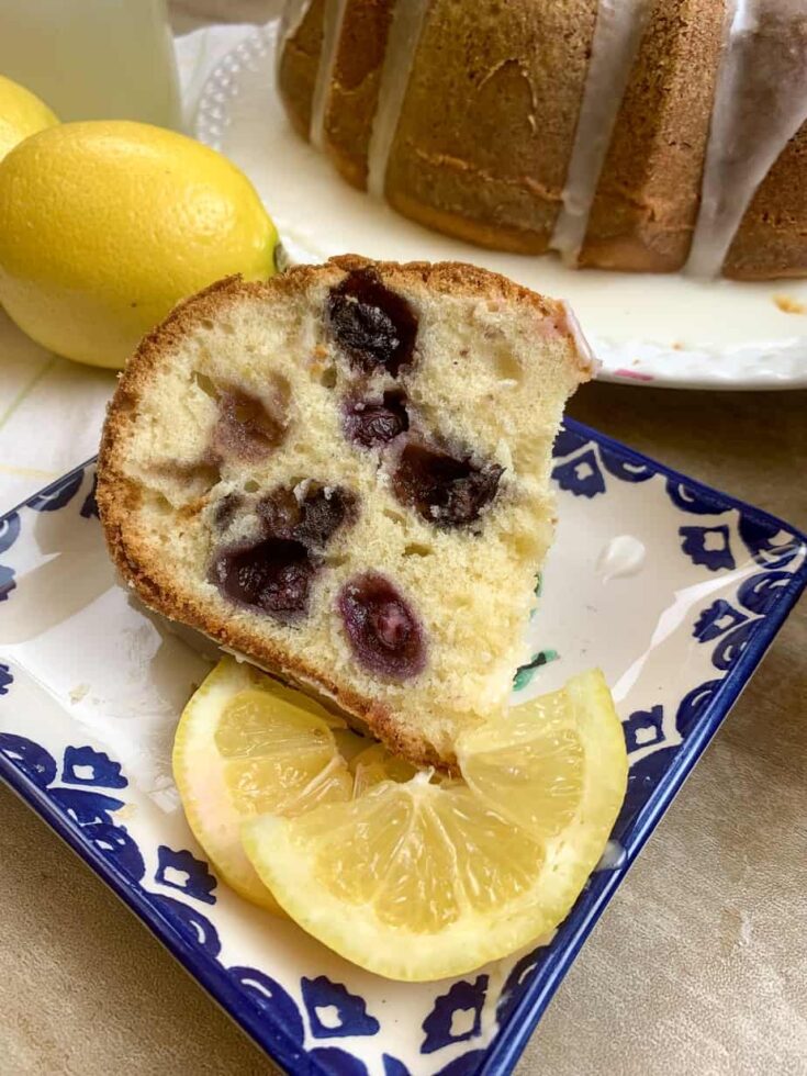 Lemon blueberry cake on a plate with a lemon