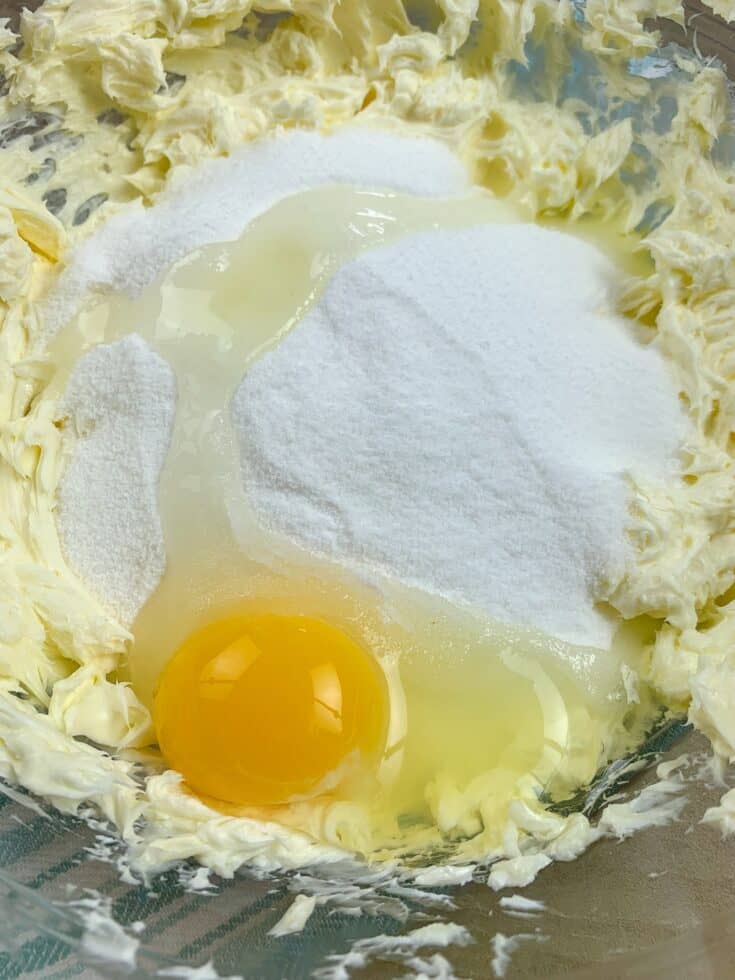 Butter, sugar, cream cheese, and an egg in a bowl