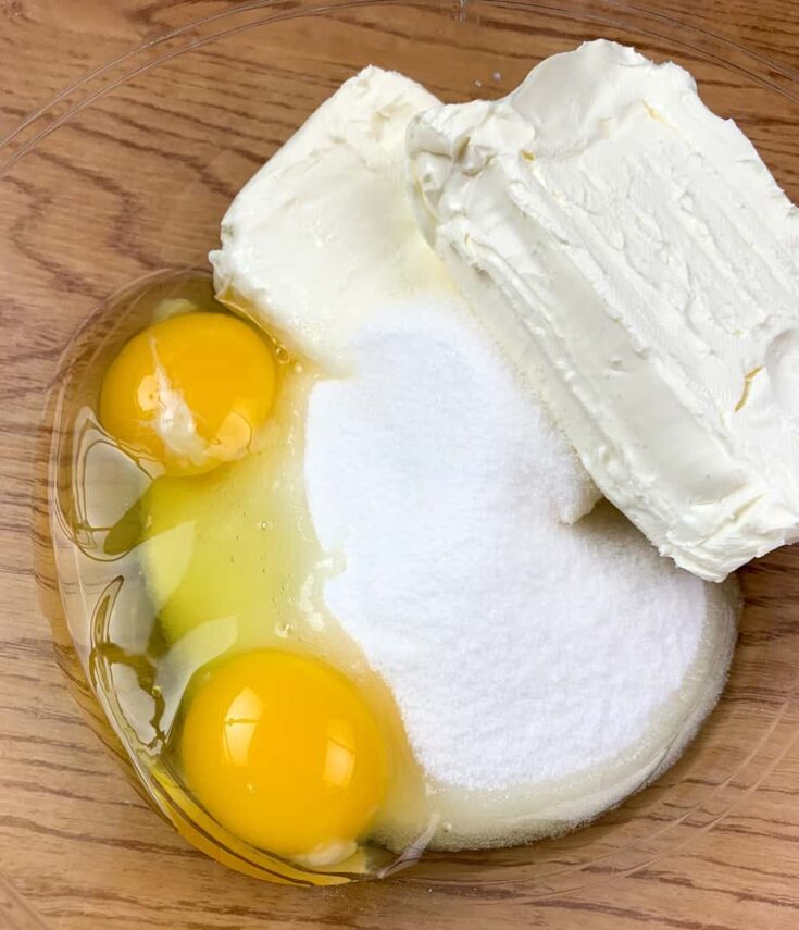 Eggs, sugar, and cream cheese in a glass bowl