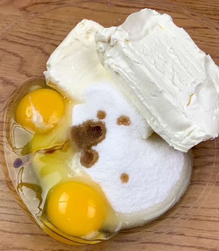 Cream cheese, eggs, vanilla extract, and cream cheese in a glass bowl.