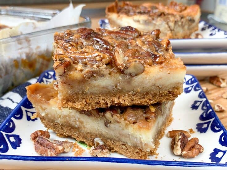 Pecan pie cheesecake bars stacked on a plate together