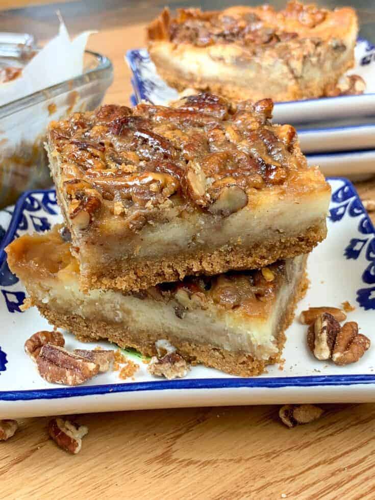 Pecan pie cheesecake bars stacked on a plate