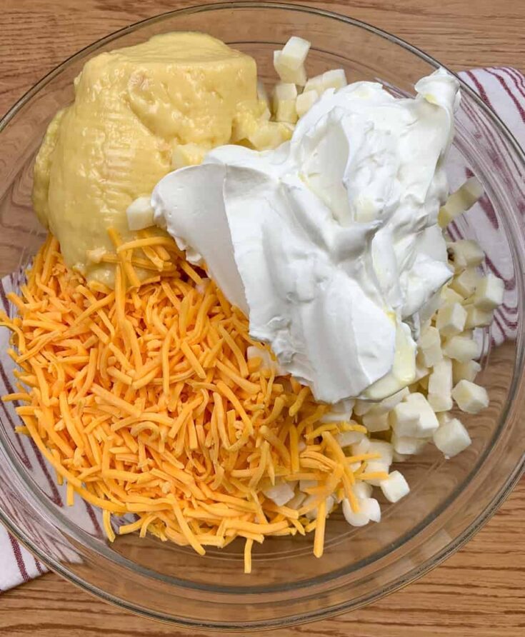 Cheddar cheese, sour cream, cream of chicken soup, and frozen cubed potatoes in a large bowl.