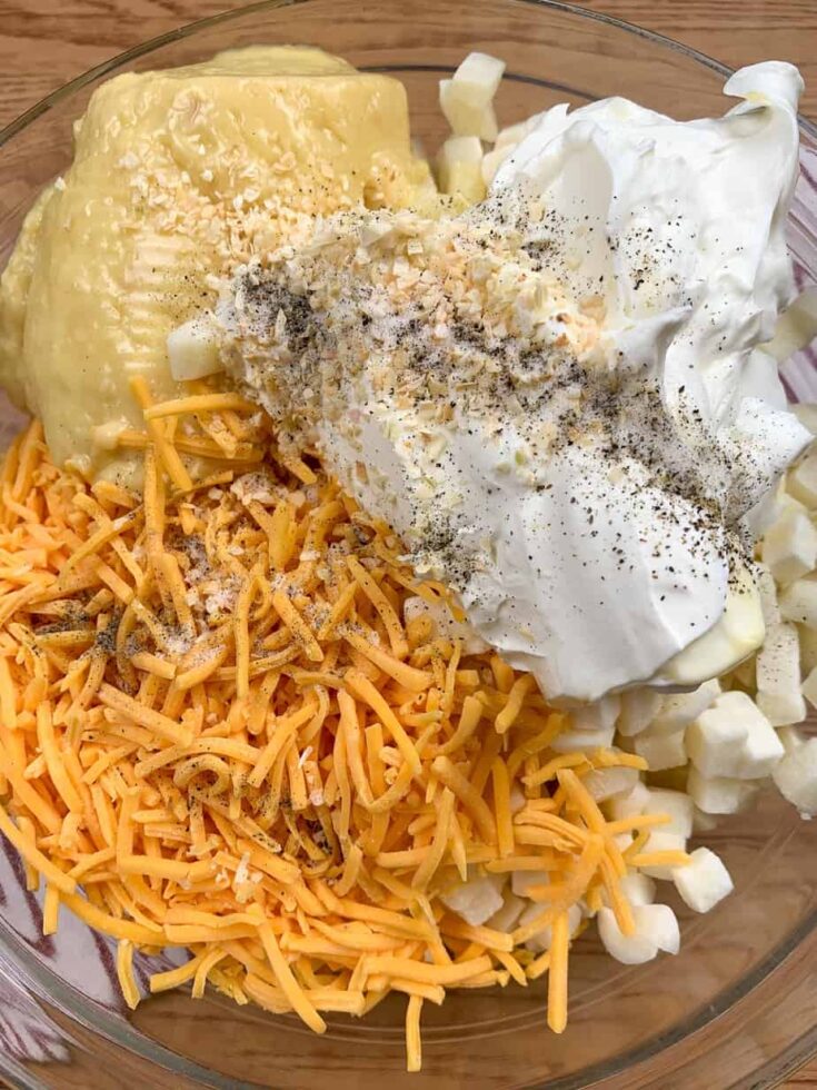 Cubed potatoes, sour cream, shredded cheddar cheese, and cream of chicken soup in a large glass bowl