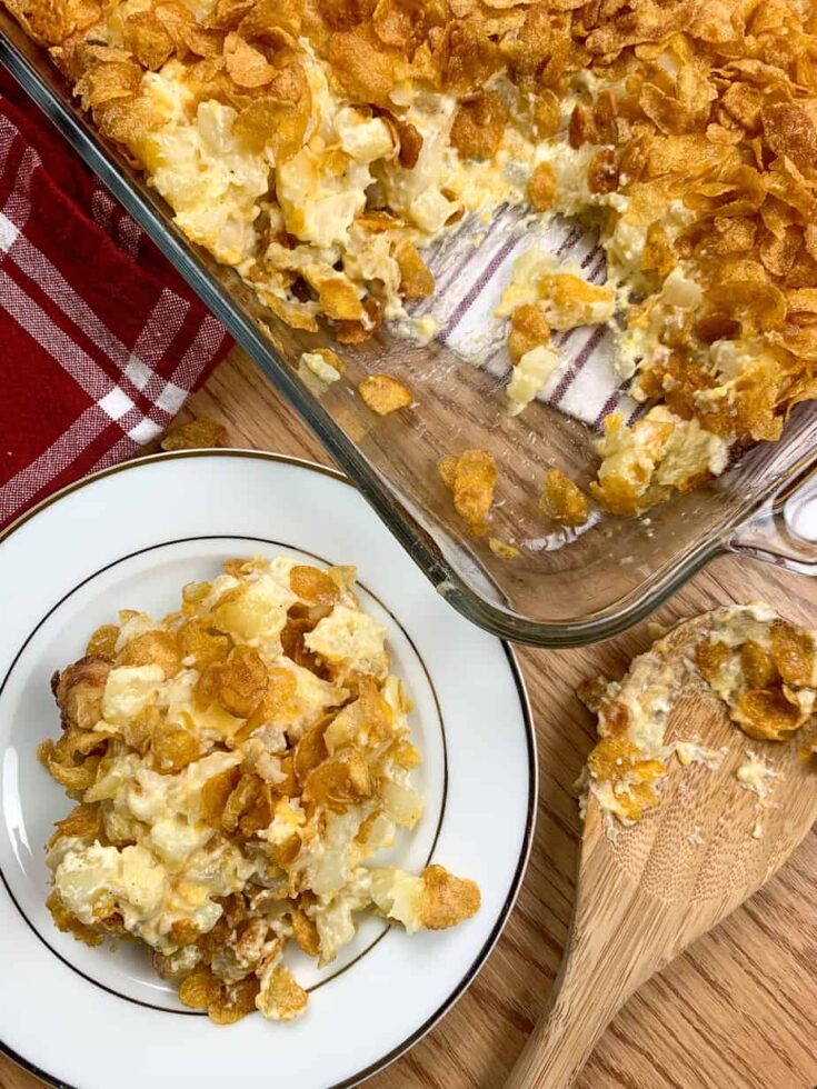 Funeral potatoes on a plate next to a casserole dish