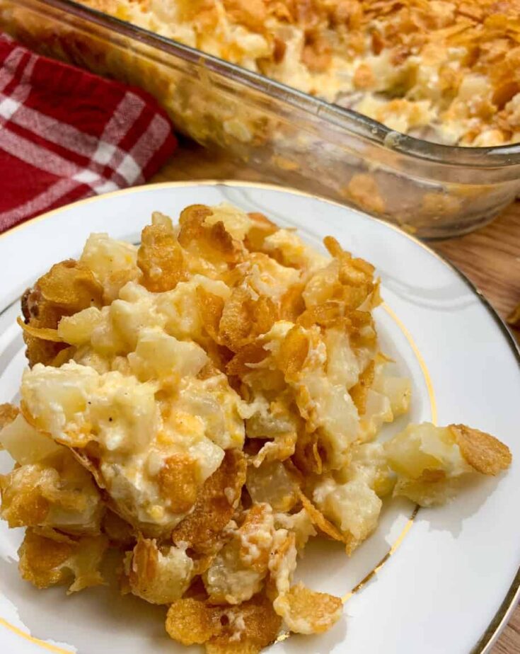 Funeral potatoes on a plate next to a casserole dish