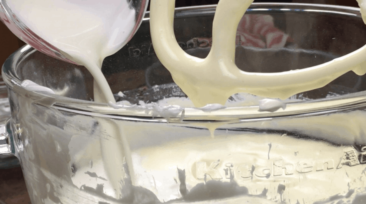 Heavy cream being poured into a bowl with cheesecake ingredients